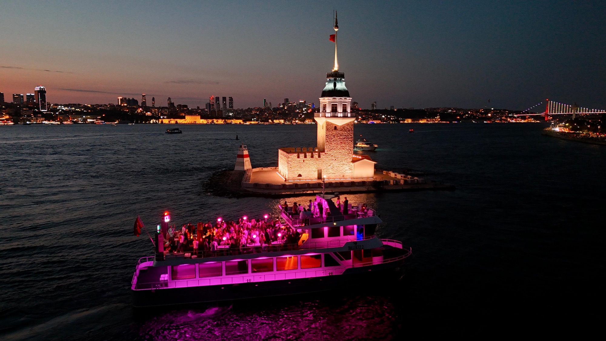 The party boat lit up pink sailing past Maiden's Tower (Kız Kulesi) on the Bosphorus at night