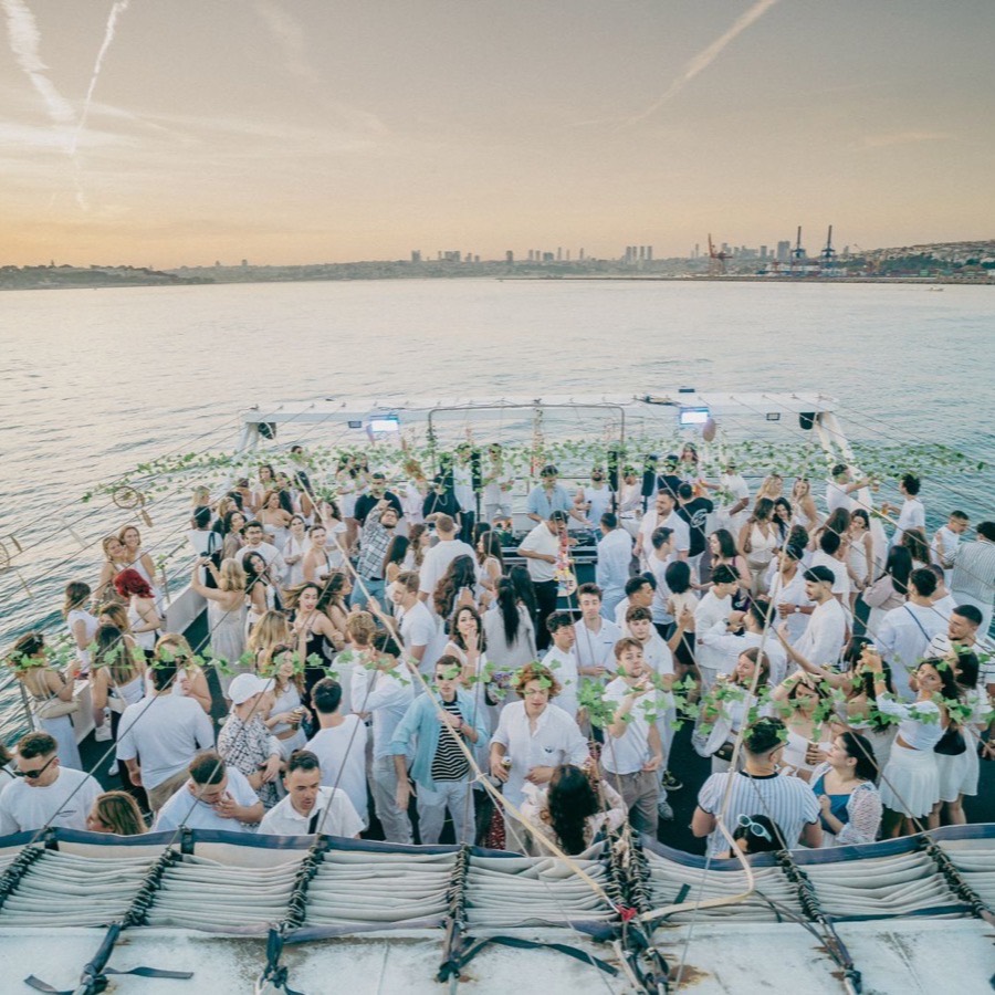 Aerial view of the crowd dancing on deck at sunset with the Istanbul skyline behind