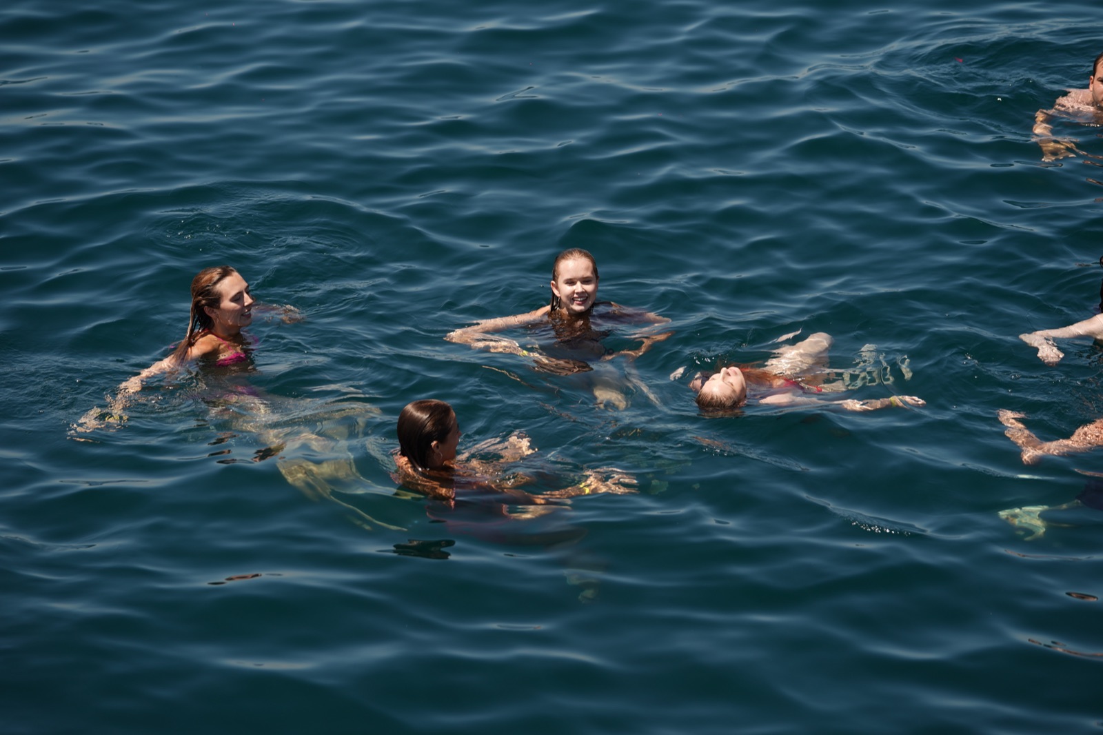 Guests swimming and floating in the open water during a swim stop