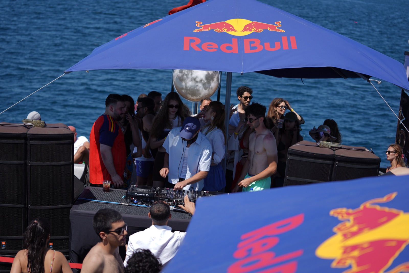 DJ performing under a deck umbrella on the swim boat party, Bosphorus in the background