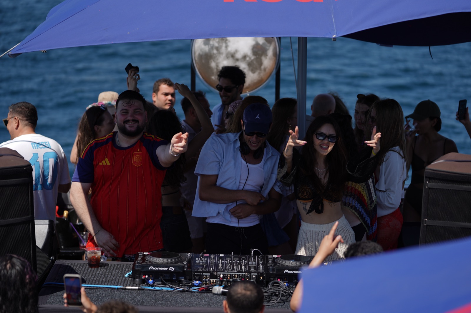 Guests dancing on deck under a sun umbrella during the daytime swim boat party