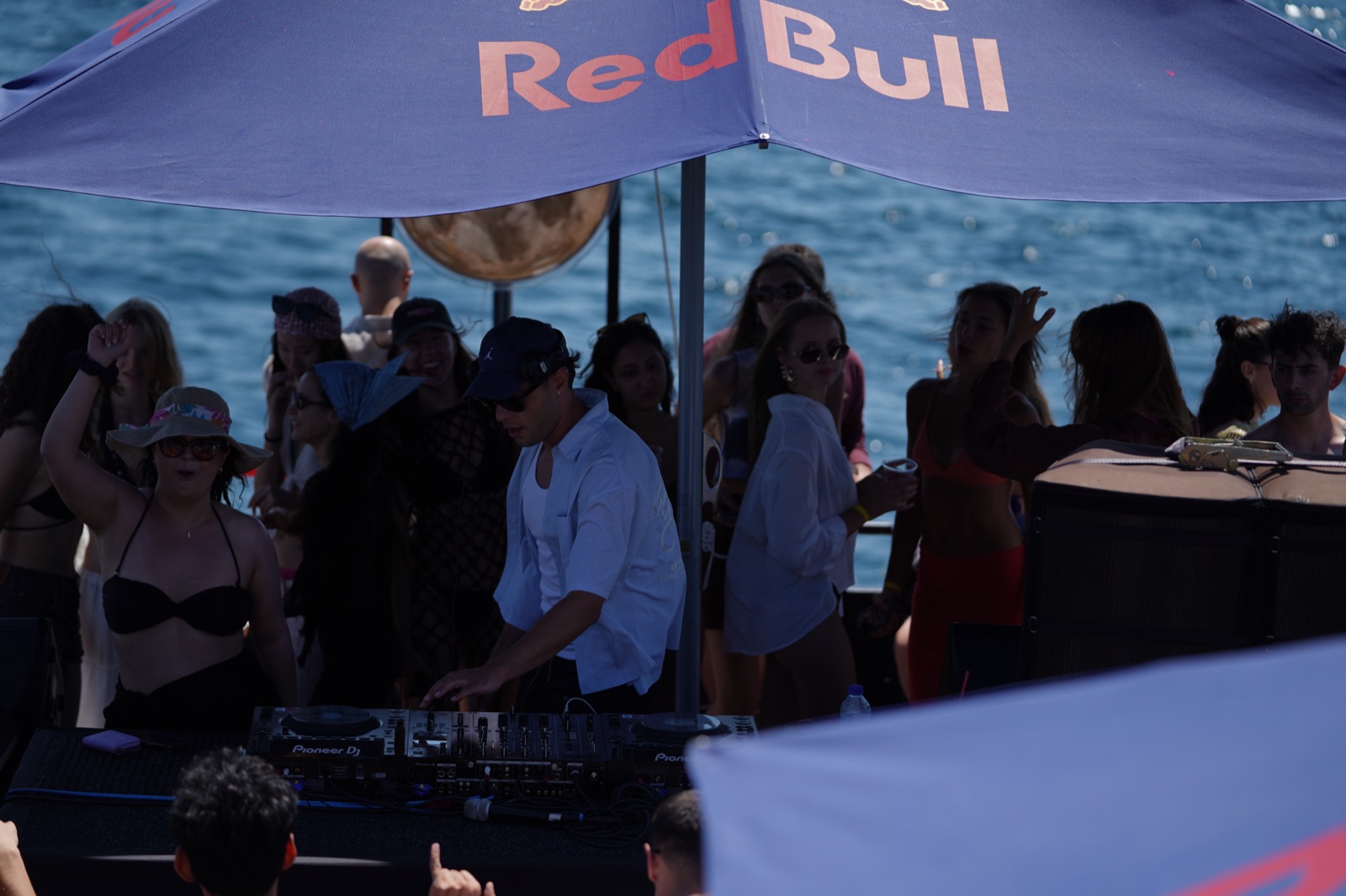 DJ set on deck with guests dancing in the shade during the swim boat party